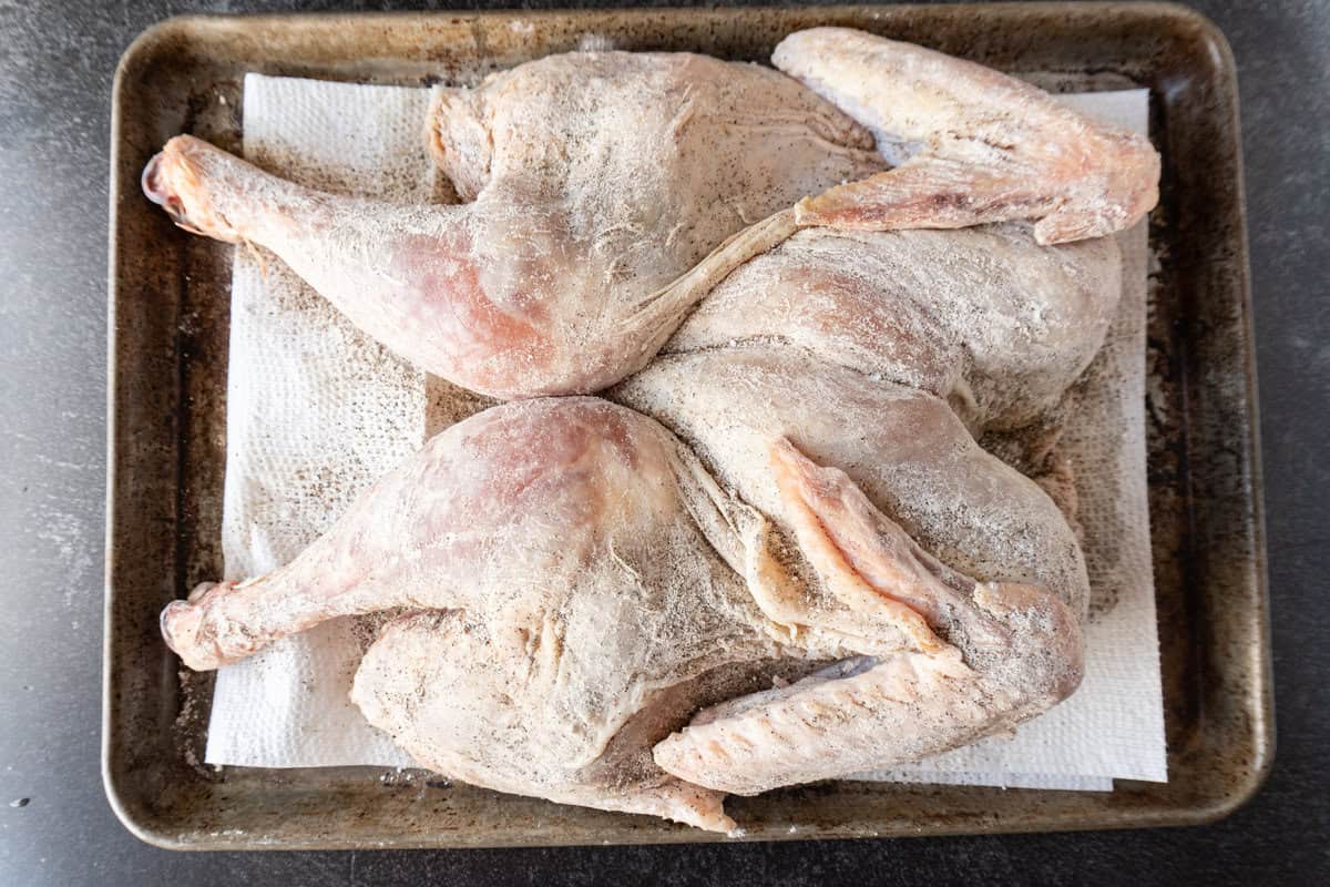 raw turkey with salt mixture rubbed on sitting on baking sheet.