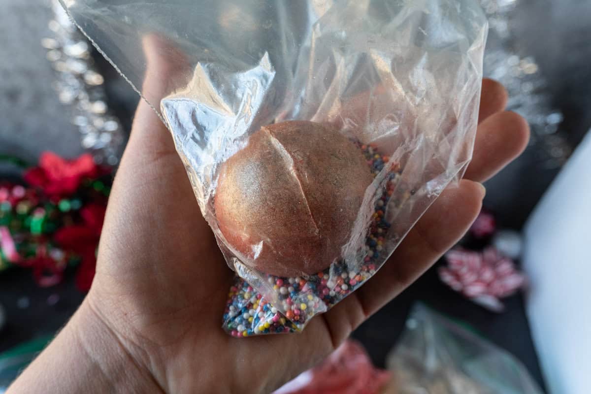rolling hot cocoa bomb in luster dust and sprinkle bag