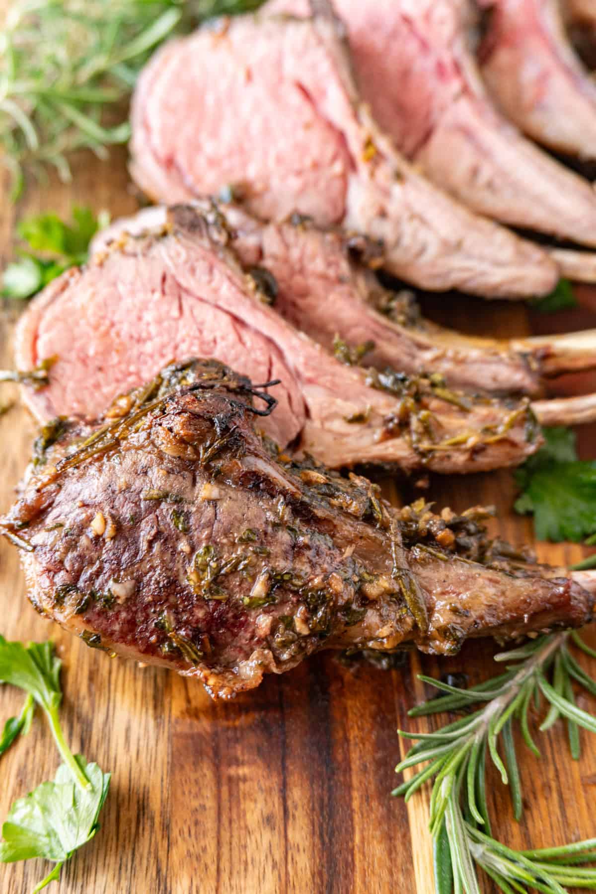 Herb Crusted Rack of Lamb with golden cooked crust, sliced on cutting board.