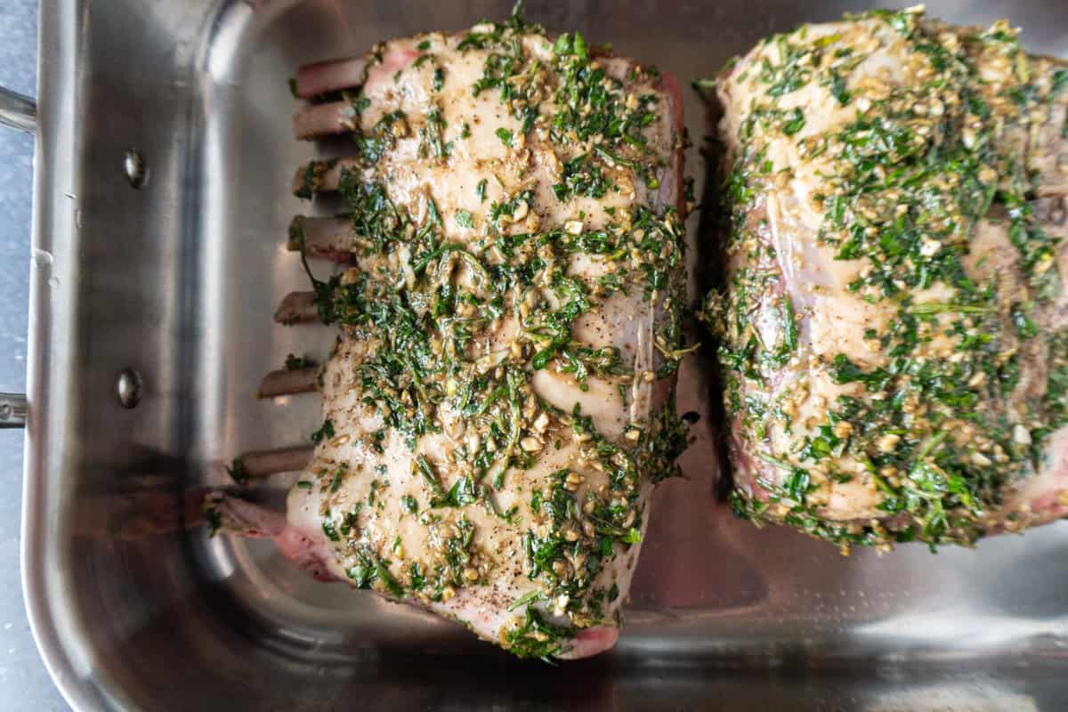 uncooked rack of lamb with herb marinade rubbed all over.