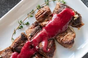 filet medallions with blackberry sauce on white platter.
