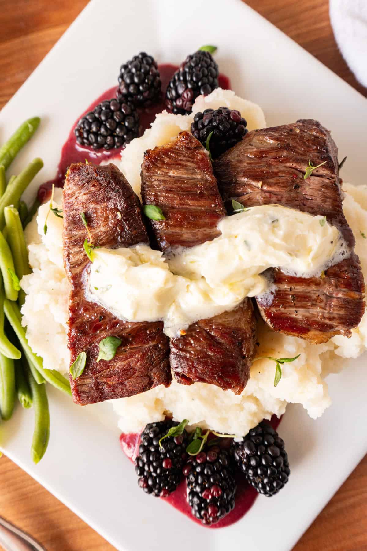 filet medallions on top of mashed potatoes with herb buter on top