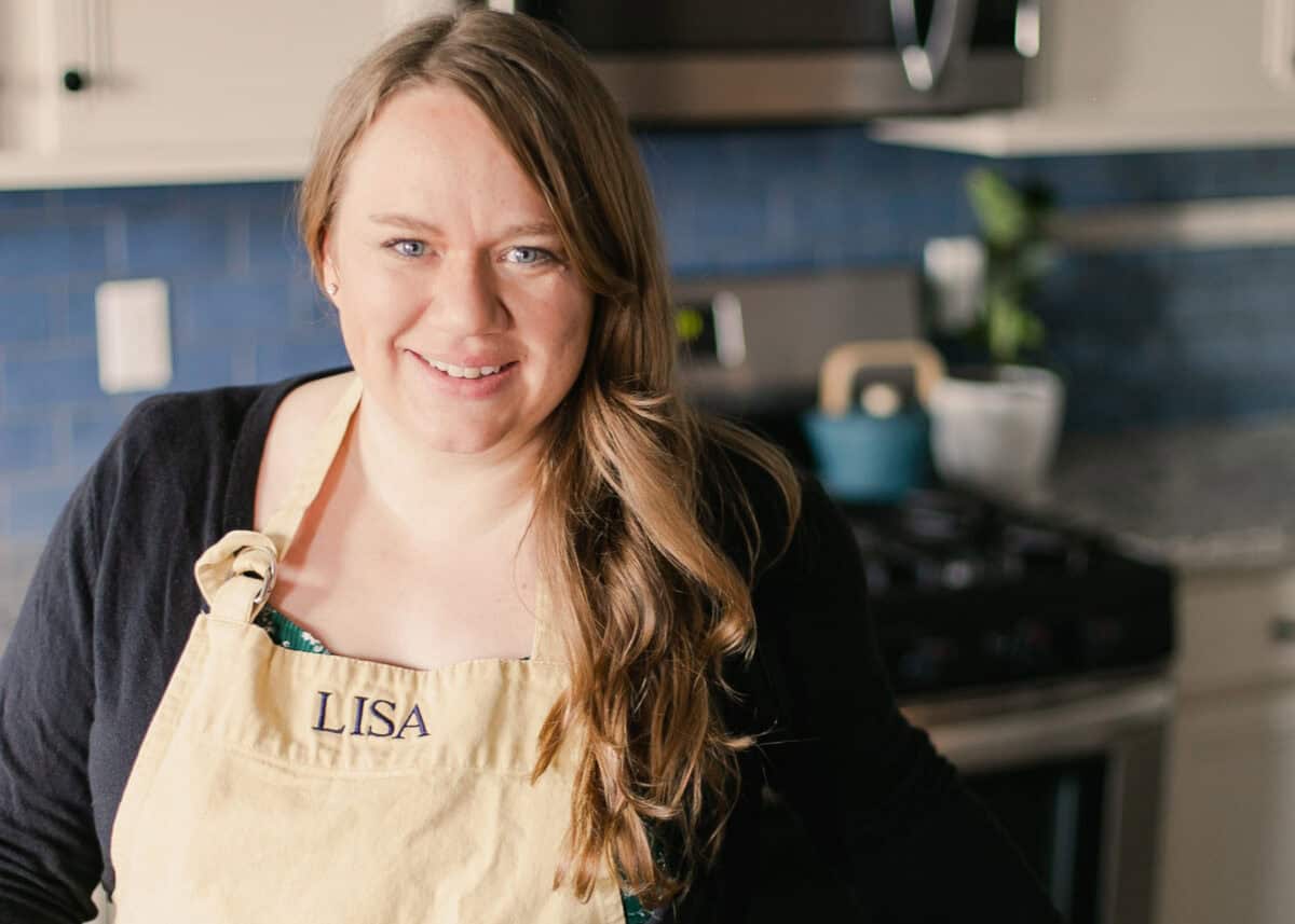 Lisa with yellow apron standing in kitchen