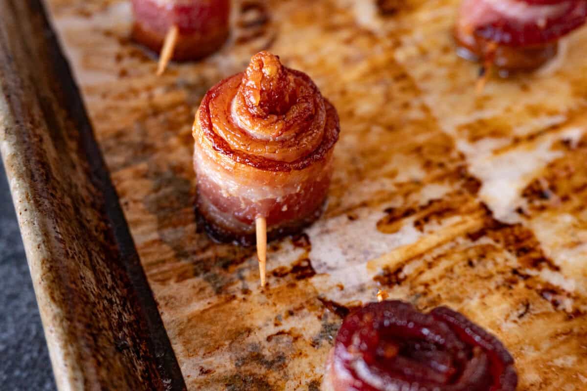 rolled bacon with toothpick through the base on baking sheet.