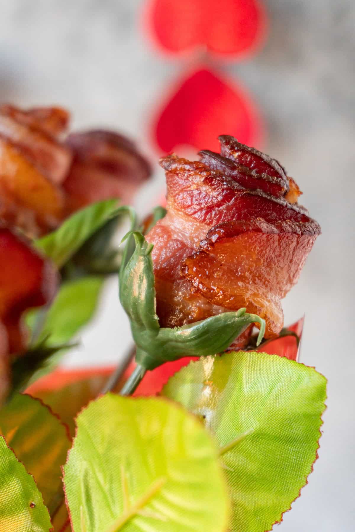 single bacon rose on fake stem with leaves.