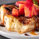 churro cheesecake bar topped with caramel sauce and chocolate sauce and strawberries featured image