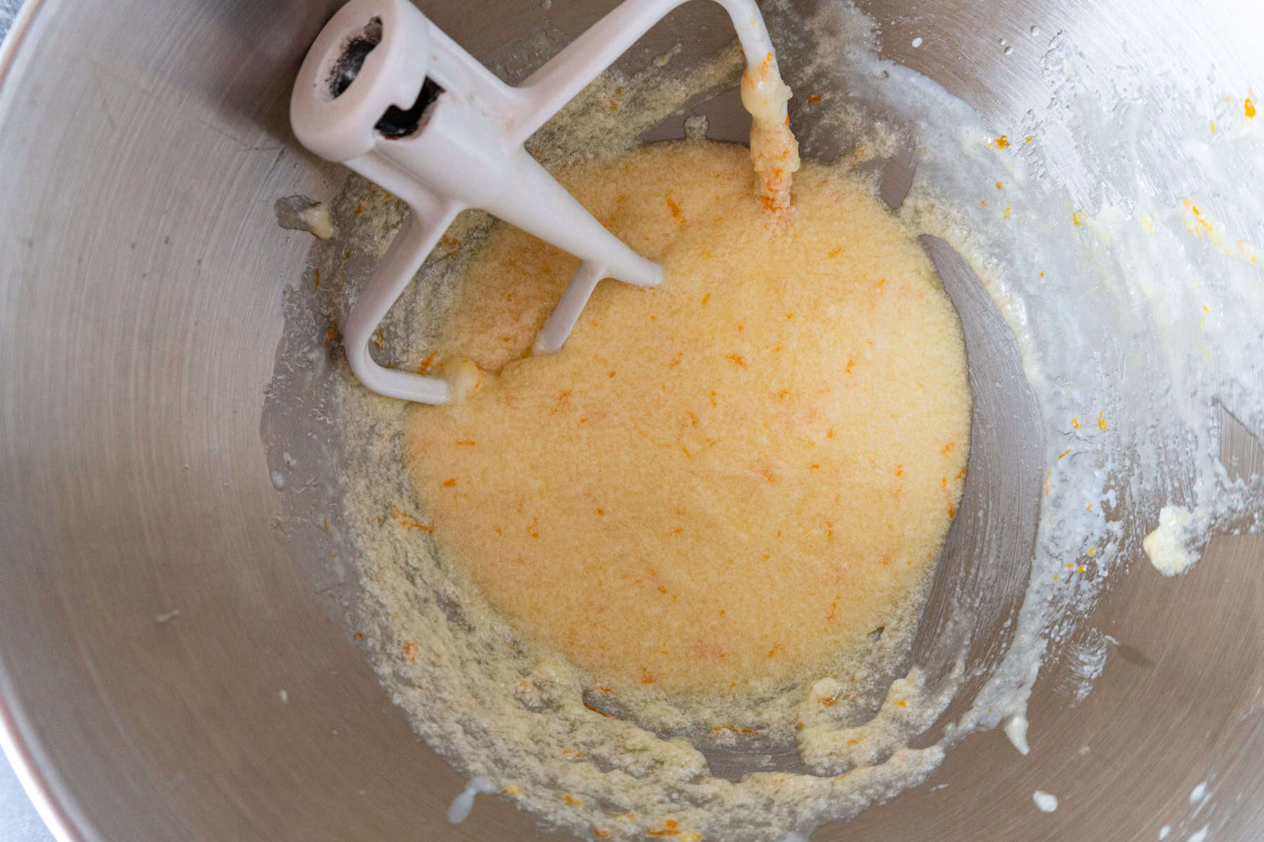 A mixer is mixing a batter with orange juice.
