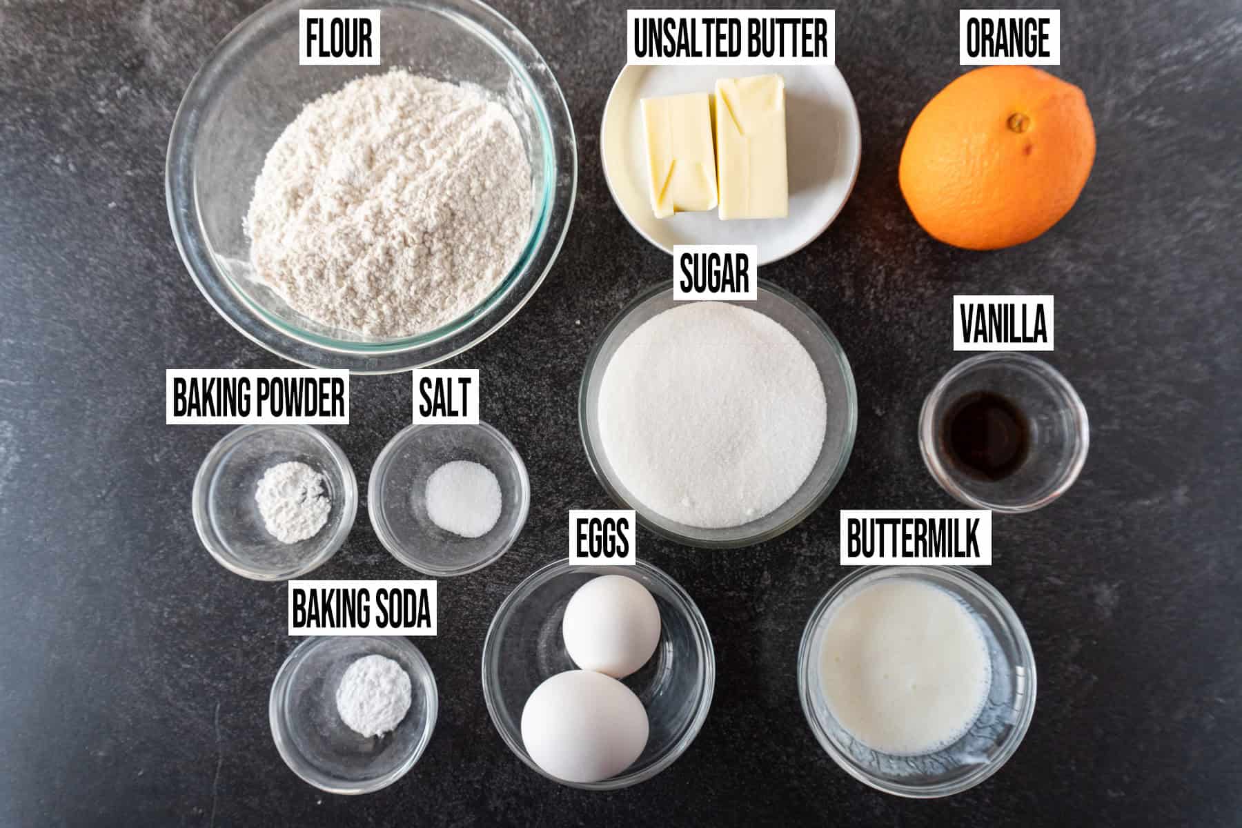 Ingredients for orange cupcakes in individual bowls and labeled..