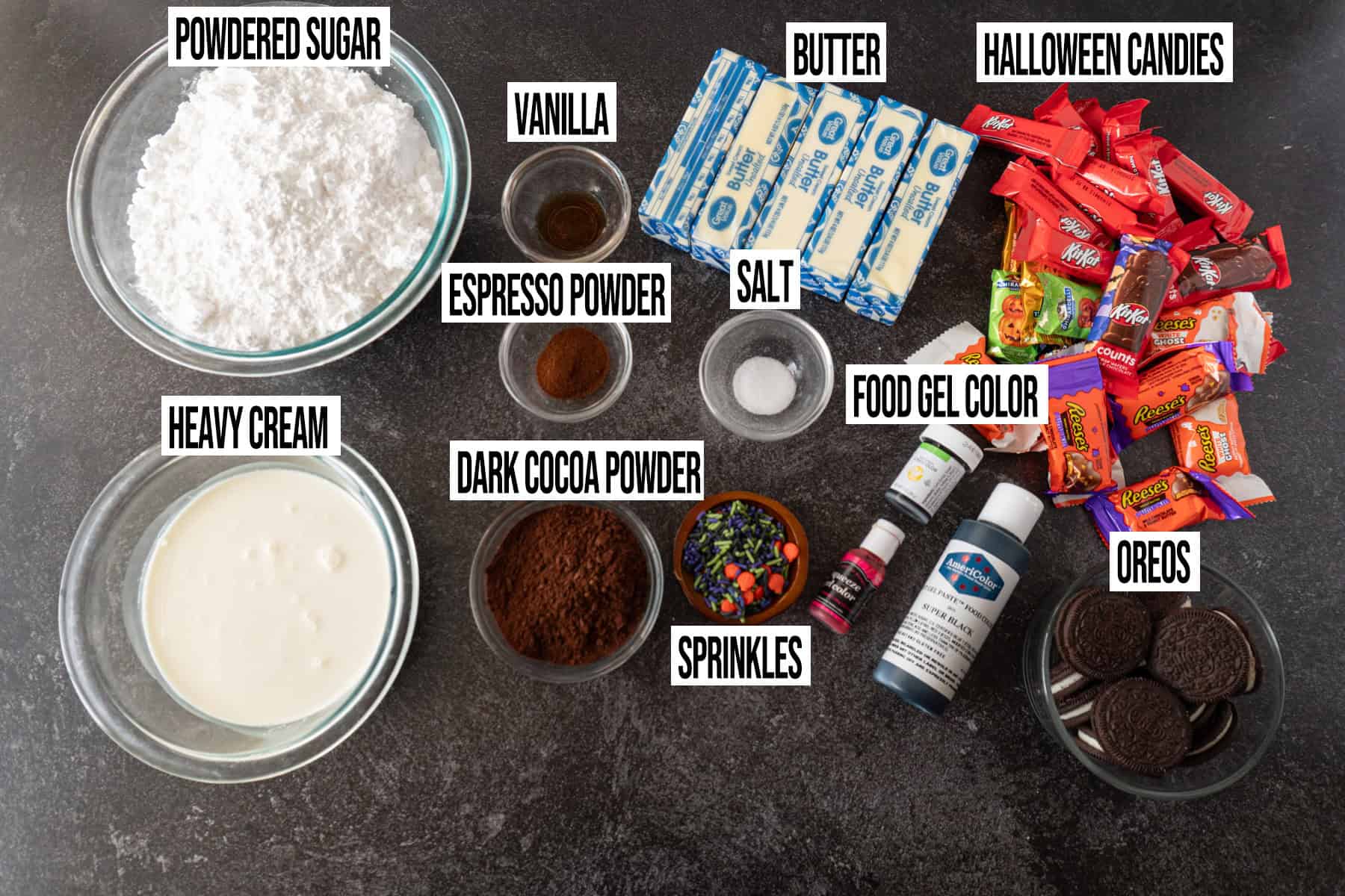 Halloween Cake Frosting and Decoration ingredients in individual bowls and labeled.